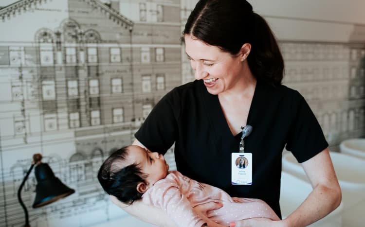 Care provider holding a baby and smiling